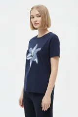 Remera de manga corta color azul marino con cuello redondo y estampado frontal de una flor en tonos celestes y blancos.