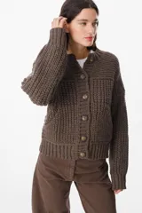 Saco de punto grueso color chocolate, con cuello redondo, cierre frontal con botones grandes y diseño de textura acanalada. Presenta un calce relajado y mangas largas con puños ajustados.
