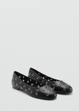 Zapato tipo bailarina color negro con diseño troquelado decorado con ojales metálicos plateados, punta redonda y suela plana.