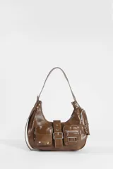 Cartera de hombro color marrón, confeccionada en cuero vegano con acabado brillante. Presenta un diseño estilo hobo con múltiples bolsillos frontales, uno con solapa y broches metálicos y otro con cierre, además de una hebilla central decorativa y herrajes plateados.