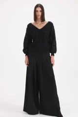 Pantalon de corte ancho y tiro alto, con pinzas frontales que aportan volumen y caída fluida.