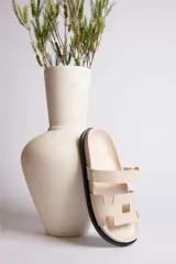 Sandalia plana color beige con dos tiras anchas en el empeine y suela negra.