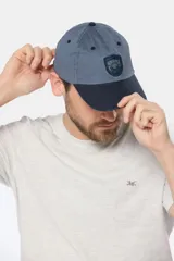 Gorro tipo gorra con visera de lona color azul, con parche tejido frontal que presenta diseño de paisaje y mar.