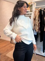 Sweater de punto color blanco, con cuello alto y detalle de escote en V con terminaciones desflecadas. Presenta mangas largas con puños acanalados y un diseño de calce holgado.