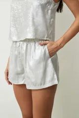 Short de tiro medio en color dorado con acabado metalizado, diseño holgado y bolsillos laterales.