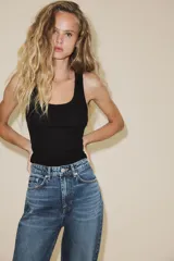 Jeans de tiro alto con diseño de cinco bolsillos, trabillas para cinturón y cierre frontal con cremallera y botón metálico.