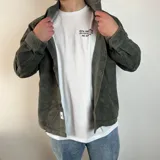 Sobrecamisa de pana en color tostado, con cierre frontal de botones, cuello clásico y dos bolsillos frontales con solapa y botón.
