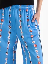 Pantalón de corte holgado y piernas rectas, confeccionado en popelina satinada de color celeste con estampado floral en franjas verticales. Cuenta con cintura elastizada y bolsillos delanteros.