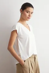 Remera blanca de manga corta, con cuello en V decorado con detalles de vainillas.