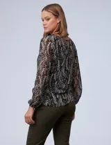 Blusa de gasa estampada en blanco y negro, marca Tahari. Tiene cuello redondo con escote en V y lazo, mangas largas con puño elastizado y forro a tono.
