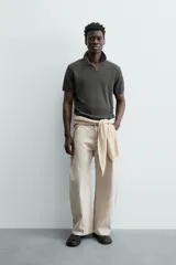 Jersey de punto color verde oliva, de calce relajado (relaxed fit), con cuello solapa y abertura frontal en forma de V. Es de manga corta y presenta acabados en rib en puños y ruedo.