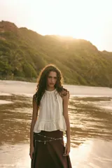 Top de gasa color menta con cuello halter y lazada posterior. Presenta detalles de bordados calados a tono y un bajo con terminación en volante.