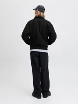 Campera bomber negra con cuello camisero, cierre frontal completo y bolsillos laterales, con puños y dobladillo acanalados.