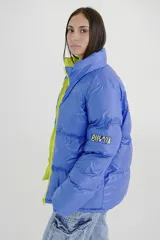 Campera puffer reversible de corte holgado, con cuello alto y cierre frontal. Un lado es de color azul vibrante con detalles en verde lima en el cierre y el interior, y el otro lado es de color negro.