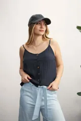 Musculosa color blanco roto con escote en V y botones frontales. La tela presenta una textura arrugada o plisada.