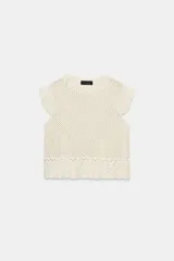 Top de cuello redondo y mangas sisa con volantes, confeccionado en tejido de punto calado con algodón y bajo con detalle de volantes.