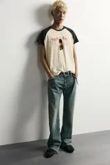 Camiseta regular fit de corte clásico con efecto lavado, cuello redondo negro y mangas cortas ranglán negras. El cuerpo es de color blanco con estampa frontal inspirada en automovilismo con el texto "Asphalt Speed".