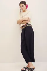 Pantalón negro de vestir de corte ancho y relajado, con cintura alta y detalles sutiles en el diseño.