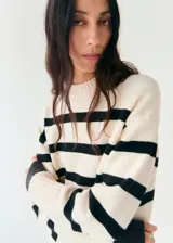 Chaleco oversize de punto con diseño a rayas horizontales en color crudo y negro, cuello redondo y mangas sisa con amplios ribetes elásticos.