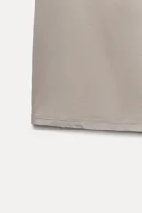 Camiseta blanca ajustada de poliamida con tirantes anchos y escote redondo.