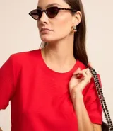 Blusa blanca de poliéster con cuello redondo, mangas cortas, cierre trasero en forma de gota, pequeñas aberturas laterales y acabados en pespuntes en las mangas y el cuello.