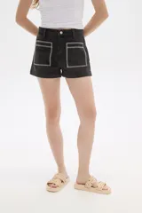 Short de jean color azul oscuro, de calce alto y ajustado al cuerpo. Presenta dos bolsillos frontales cuadrados con bordado decorativo en color blanco.