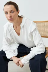 Blusa blanca de bambula con cuello en V y volados en cuello, mangas y frente.