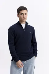 Buzo de punto con medio cierre frontal, cuello elevado y puños acanalados. Presenta un pequeño logo bordado en el pecho.