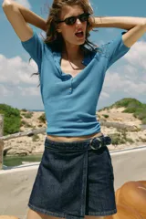 Falda pantalón cruzada de denim en color celeste, con diseño cruzado al frente, cierre frontal oculto y hebilla decorativa redonda en la cintura.