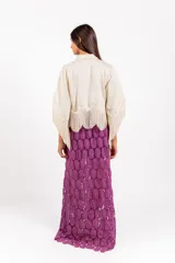Camisa corta de color beige con silueta amplia, mangas anchas tipo capa terminadas en flecos y ramos de flores bordados en el frente.