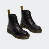 Bota de caña media Dr. Martens modelo 1460, confeccionada en cuero marrón con acabado mate. Presenta cierre de cordones con ocho ojales metálicos, costuras amarillas características en la unión de la suela y suela de goma acanalada con amortiguación de aire.