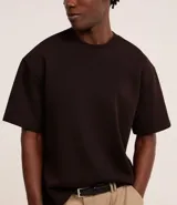 Remera de corte boxy con cuello redondo y mangas cortas, confeccionada en tejido de malla pesada con textura gomosa.