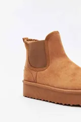 Bota corta de gamuza color tostado, tipo botineta, con paneles elásticos laterales y suela de plataforma plana.