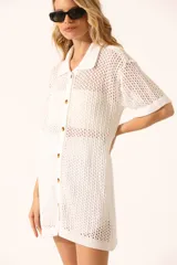 Vestido corto blanco de tejido calado con cuello tipo polo, mangas cortas y cierre frontal con botones.