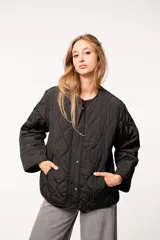 Campera capitoneada color verde oliva, con cuello redondo, cierre frontal con botones a presión, bolsillos laterales y aberturas laterales con botones.