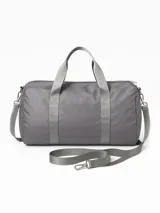 Bolso deportivo tipo duffel bag, color gris liso, con asas de mano y correa ajustable para hombro.