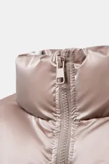 Anorak acolchado de efecto brillante con tejido cortavientos y repelente al agua. Presenta cuello subido, cierre frontal con cremallera, bolsillos delanteros con forro polar y cierre de cremallera, y mangas largas con puños elásticos. El bajo es ajustable con cordones elásticos laterales.