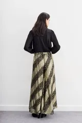 Pantalón de corte amplio y fluido, confeccionado en viscosa jacquard con hilos de lurex. Presenta un diseño de rayas diagonales con estampado de puntos dorados sobre fondo negro, cintura con elástico en la parte trasera y forrería a tono.