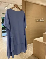 Vestido celeste de lino con corte asimétrico, más corto adelante que atrás, y diseño holgado.