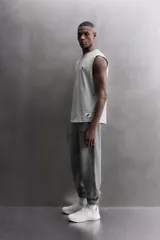 Camiseta sin mangas gris de corte regular fit, con cuello redondo. Presenta un bordado de un guante de boxeo en el pecho y un parche con logo en la parte inferior.