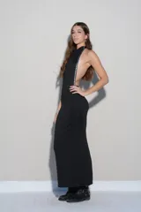 Vestido largo negro de corte ajustado, con espalda descubierta y detalle de tachas metálicas plateadas a lo largo de los laterales.