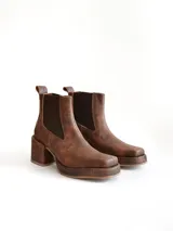 Bota tipo chelsea de cuero color chocolate con acabado texturizado, plataforma y taco cuadrado. Presenta paneles elásticos laterales en color negro.