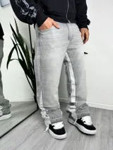 Jeans estilo flared color gris con efecto acid wash, corte ancho y bandas laterales en tono más claro. Presenta dobladillo deshilachado.