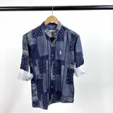 Camisa de manga larga con cuello mao y estampado de arabescos en tonos azul marino y celeste. Presenta un pequeño logo bordado en el pecho y puños con botón.