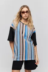 Remera oversize de manga corta con diseño de rayas verticales en tonos rojos, negros, blancos y tostados, y mangas blancas lisas.
