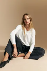 Remera de manga larga con silueta relajada y caída fluida, confeccionada en tejido suave con cuello redondo y aberturas laterales en el ruedo.