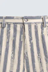 Bermuda de hombre color beige con estampado de rayas verticales azules con efecto desgastado. Corte relaxed fit, con cierre frontal de cremallera y botón, bolsillos delanteros y bolsillos traseros de plastrón.