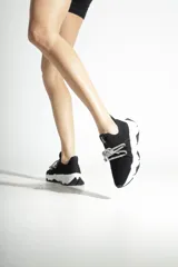 Zapatillas urbanas Schutz de tejido knit negro, con suela chunky blanca de diseño dentado y cordones decorativos de lurex brillante.