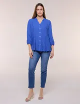 Blusa celeste de silueta suelta y textura liviana, con escote en V, cuello mao y cierre frontal de botones. Cuenta con alforzas verticales en el pecho y mangas tres cuartos con puños elastizados y detalle de galón calado.