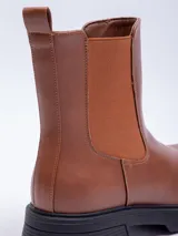 Bota Chelsea de cuero sintético color negro, con elástico lateral y suela track.